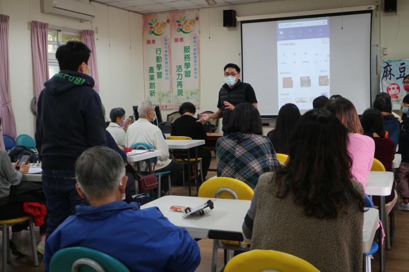 老師教學員用手機操作,下載APP程式來製作明信片。