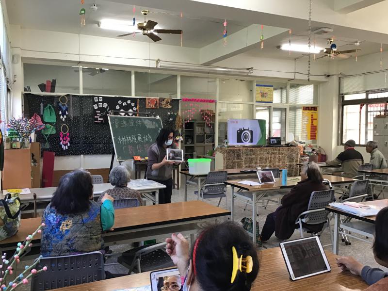 講師拿著學員的自拍照請學員一同觀看