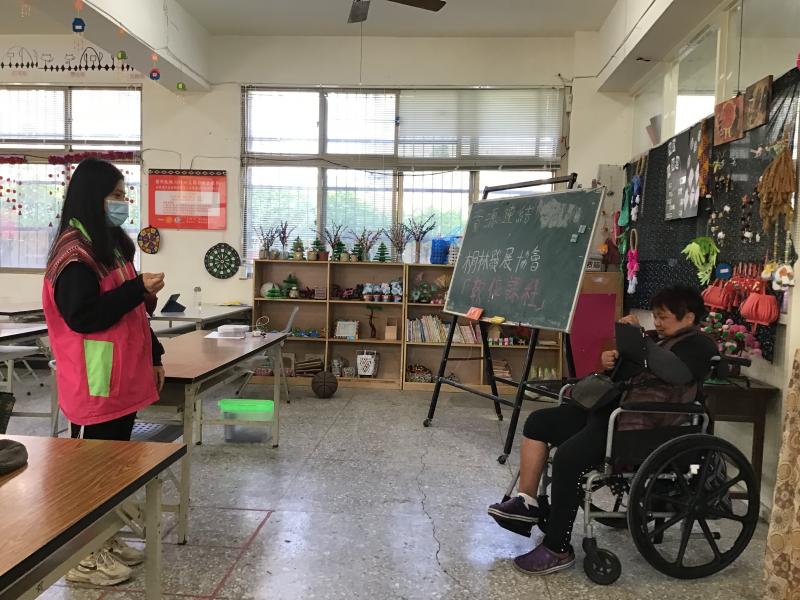 坐著輪椅的學員拿著平板對工作人員拍照