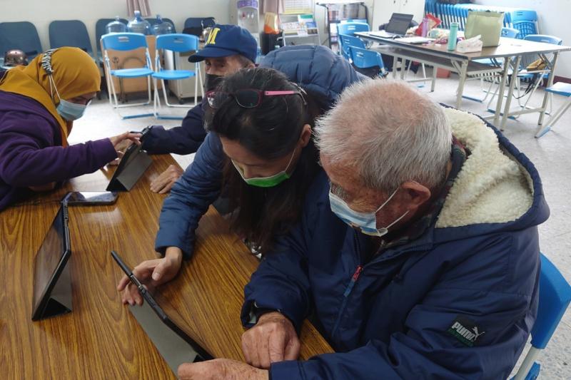 長者接受志工協助，老師也在一旁指導。