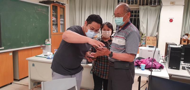 學員拿著手機問老師如何下載手機街口支付APP.