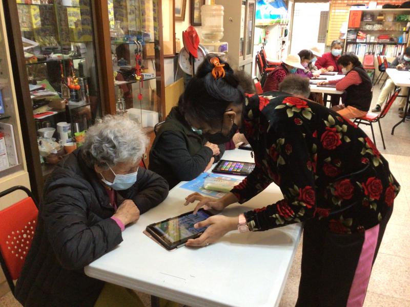 外籍家庭看護工協助指導一起來上課之社區長者平板電腦操作