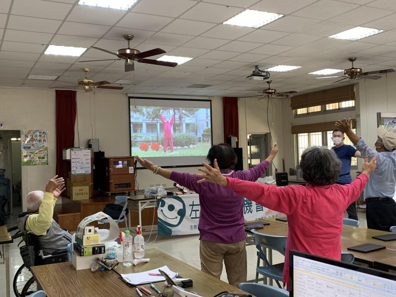 坐著輪椅的長輩認真跟著影片練功