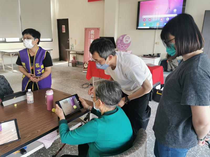 第一次使用平板的阿嬤，對於觸碰式螢幕不太理解，老師及助教走到一旁協助