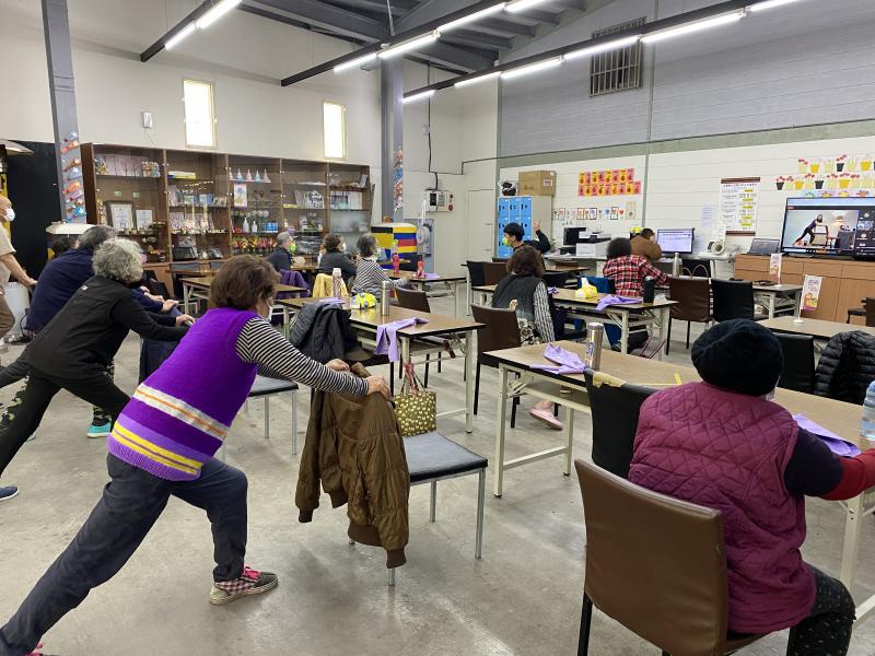 除了躺姿在教室不方便操作之外，長者或坐或站來練習動作。後排長者幾乎高齡八、九十歲，也都願意嘗試健身運動。