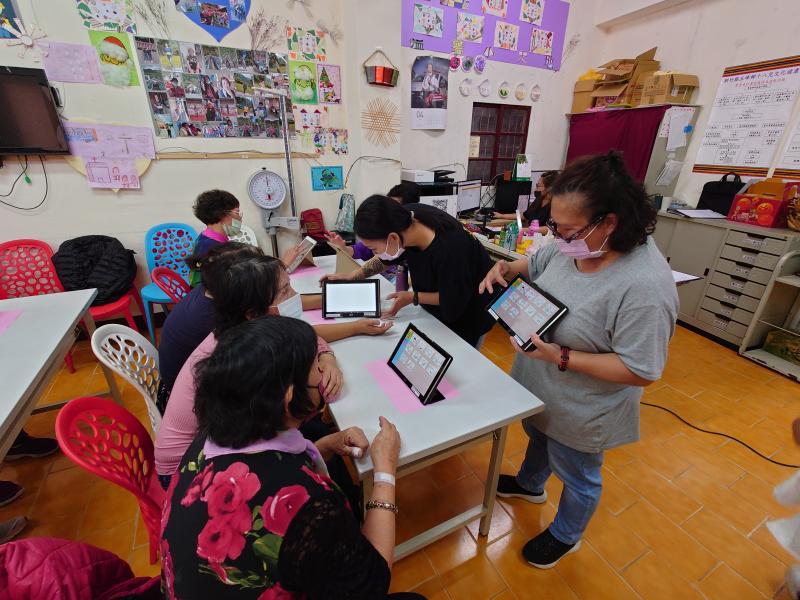 老師教導長者如何操作平板來完成屬於自己的一張圖畫。