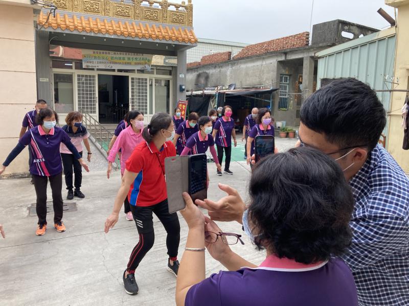 老師帶領長輩在廟前廣場，開啟直播，與觀眾分享健康操運動