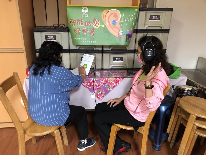 志工操作平板，學員戴著耳機接受聽力檢測