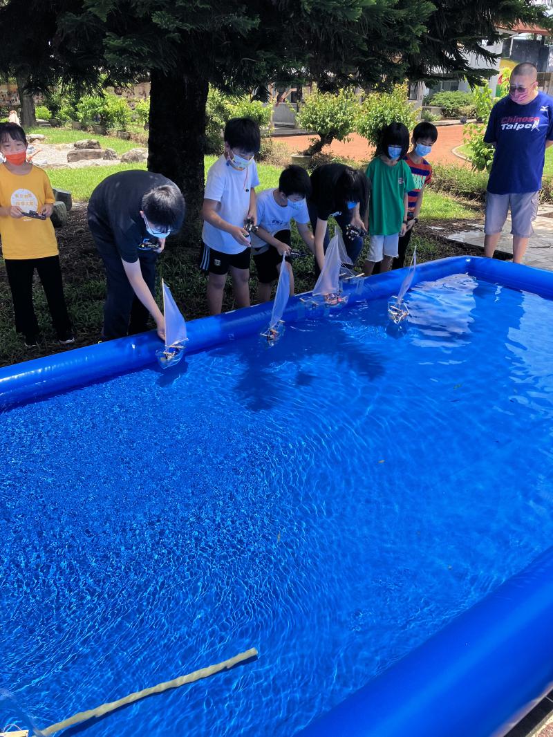 學員們在戶外將風動船放在水上測試操作控制