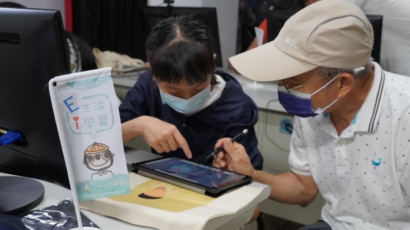 小學員教導阿公使用平板畫畫