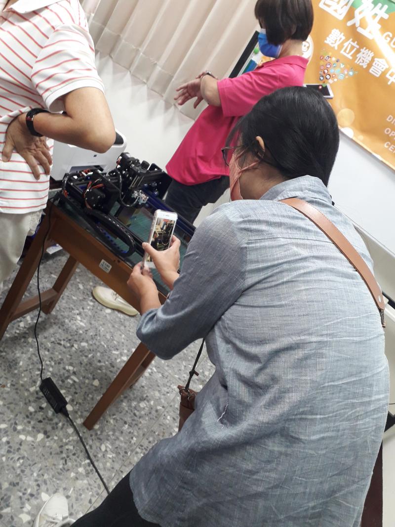 學員用手機紀錄著自己親手做的作品,利用雷雕機雷射雕刻出的作品.