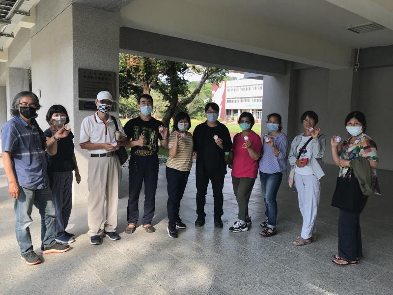 學員手拿自己繪製自畫像製成的胸章合影