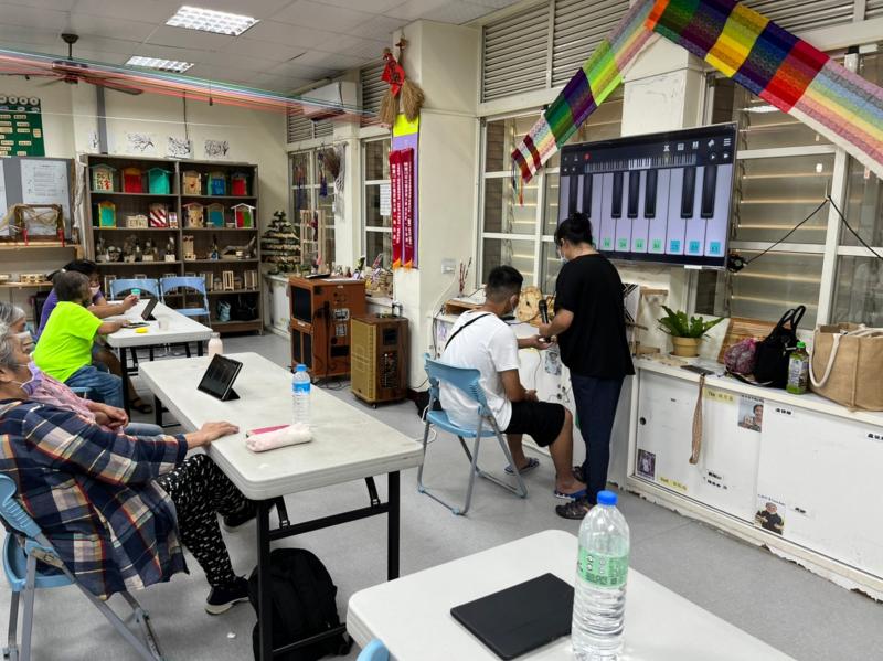 講師與學員互動，透過平板APP彈鋼琴帶領學員實作