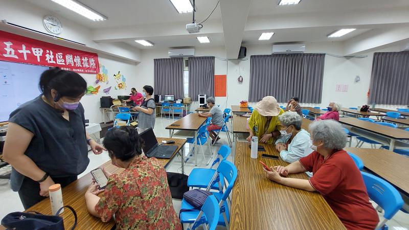 老師和志工們教導長輩使用手機上的錄音裝置，來搜尋下載想看的影音檔