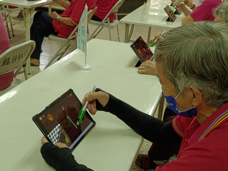 社區長輩們試試使用觸控式筆頭來使用平板用平板切水果