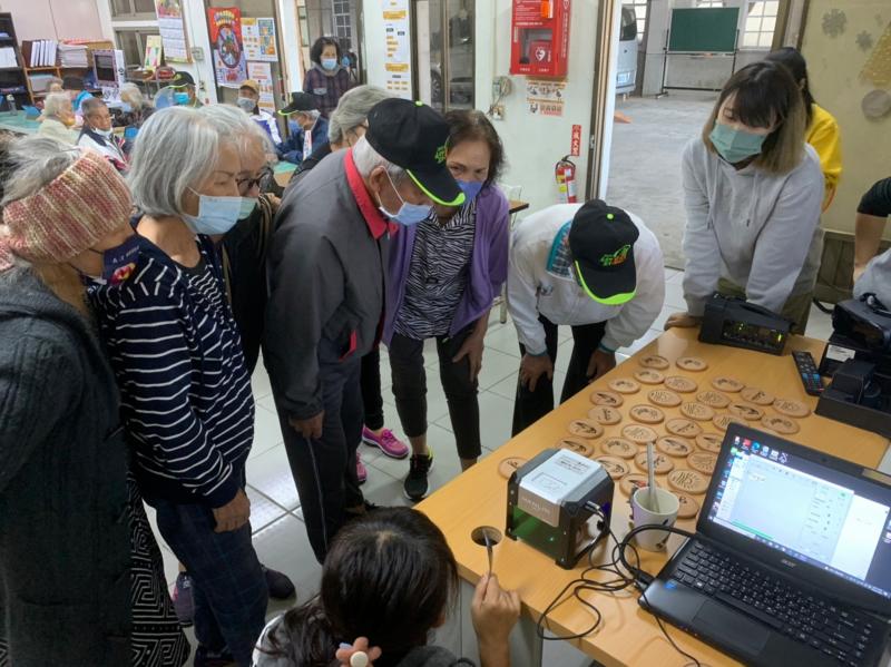 長輩體驗雷射雕刻機,互相研究討論著