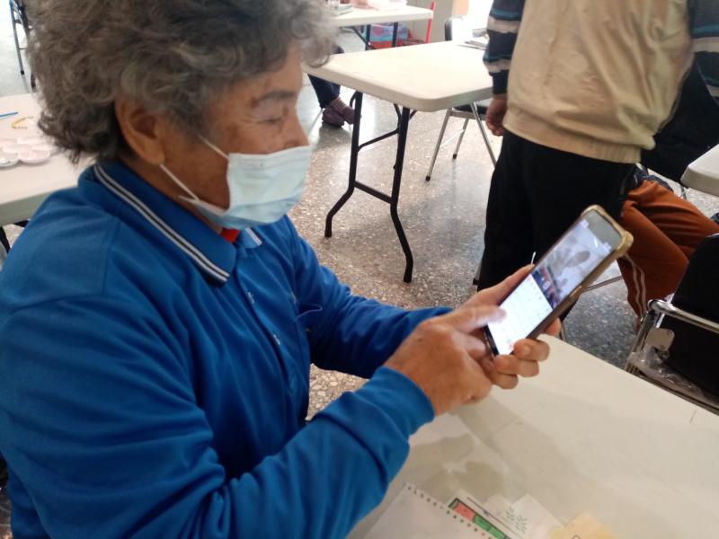 長者拿著手機將作品照片上傳群組