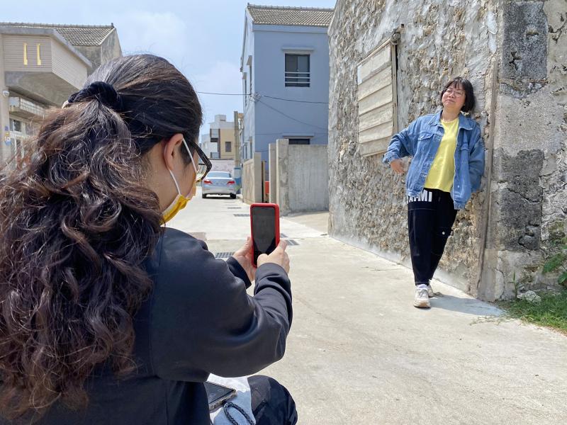 一位學員靠著石牆擔任大家的攝影模特，其他學員認真練習人像攝影