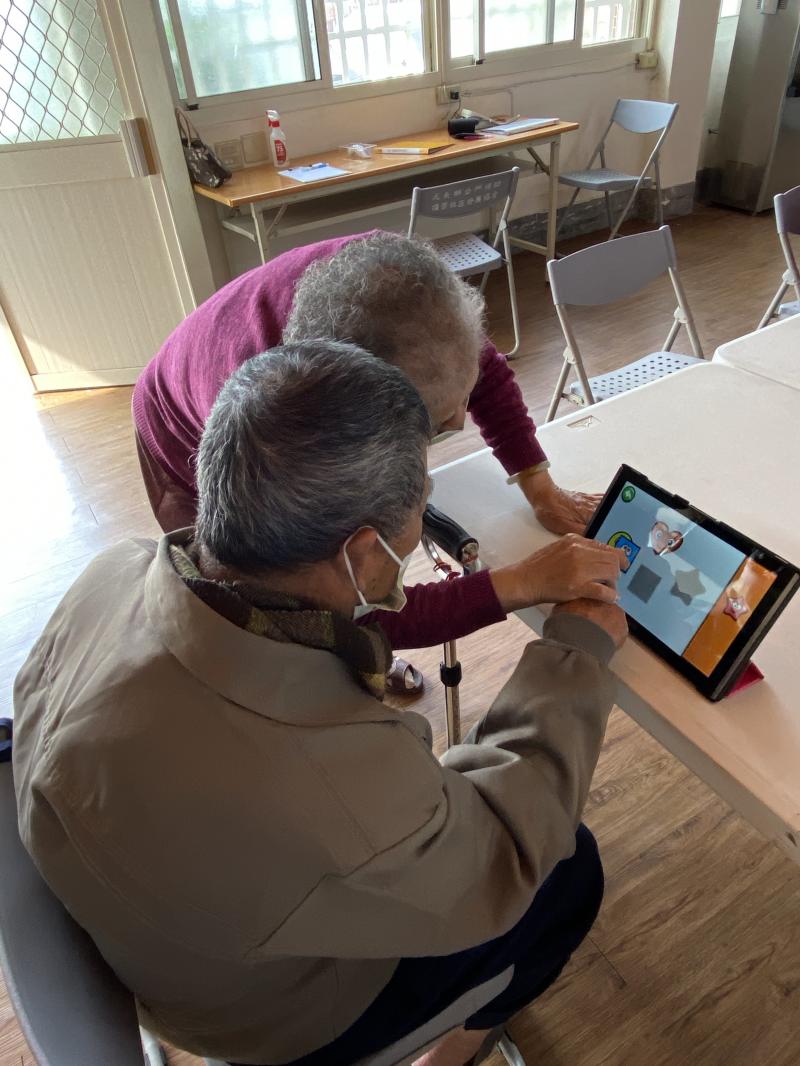 阿嬤一邊跟著老師點選操作，再次詢問老師操作方法是否正確後，立馬走到阿公身邊悉心教導如何操作，老師課程中代入讓大家熟悉平板操作的小遊戲，可以訓練老人家的眼力及手指反應能力，阿嬤一遍一遍的，陪阿公練習!