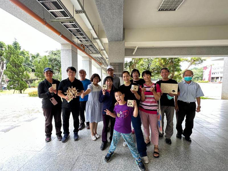 學員們雙手拿著進階課程完成的作品-時鐘、機器人藍芽音箱與老師一起合影