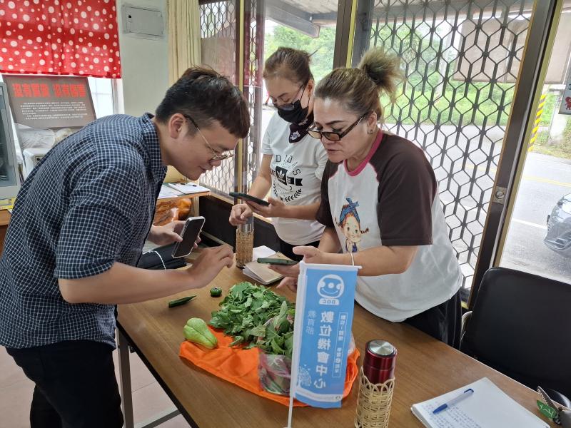 講師協助學員植物辨識APP下載，桌上的植物為講師自費購入，讓學員透過APP掃描掃描辨識並留下觀察紀錄後，於課堂尾聲應用於野菜大鍋湯讓學員一起享用