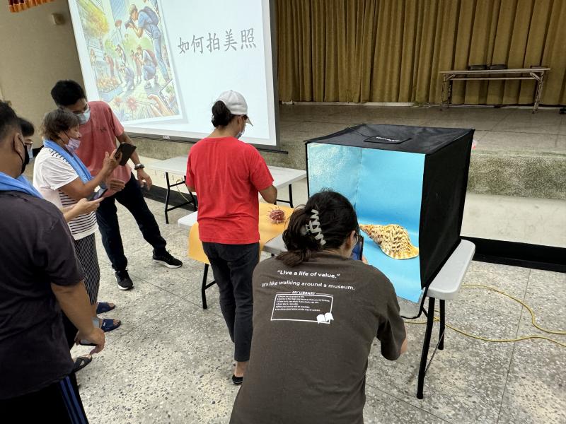 一群長者正在學習使用智能手機拍照，專注於拍攝貝殼等對象。這個課程增強了他們的攝影技能和科技信心，豐富了生活。