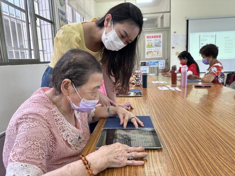 老師協助學員平板益智遊戲的操作