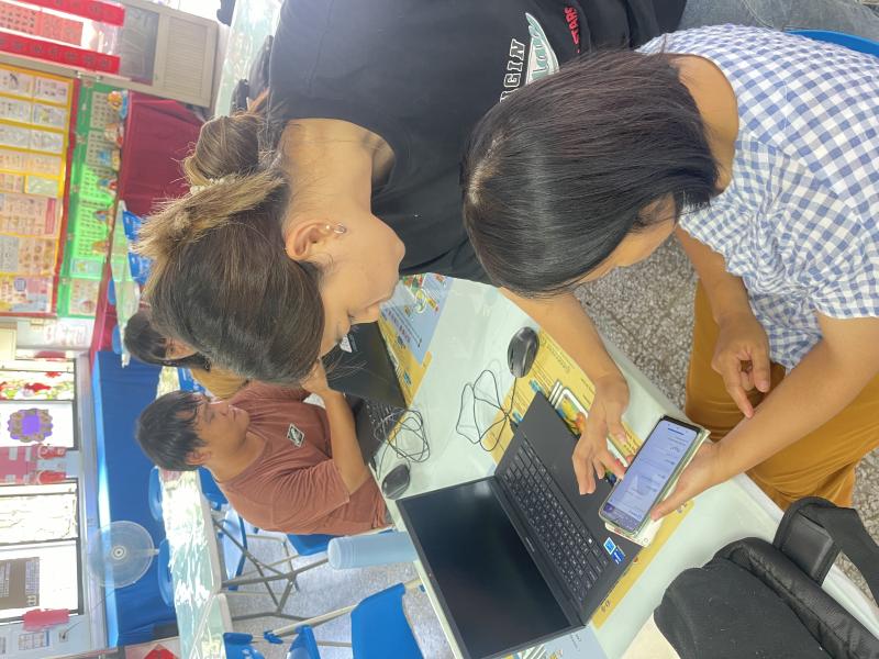 老師跟學員的學習互動,正細心指導學員如何使用手機連接電腦。學員們認真學習，努力提升自己的科技技能,希望能跟上進度