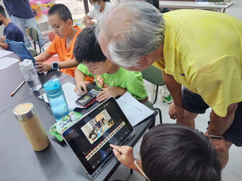 學員使用手機剪輯影片，阿公在旁邊看