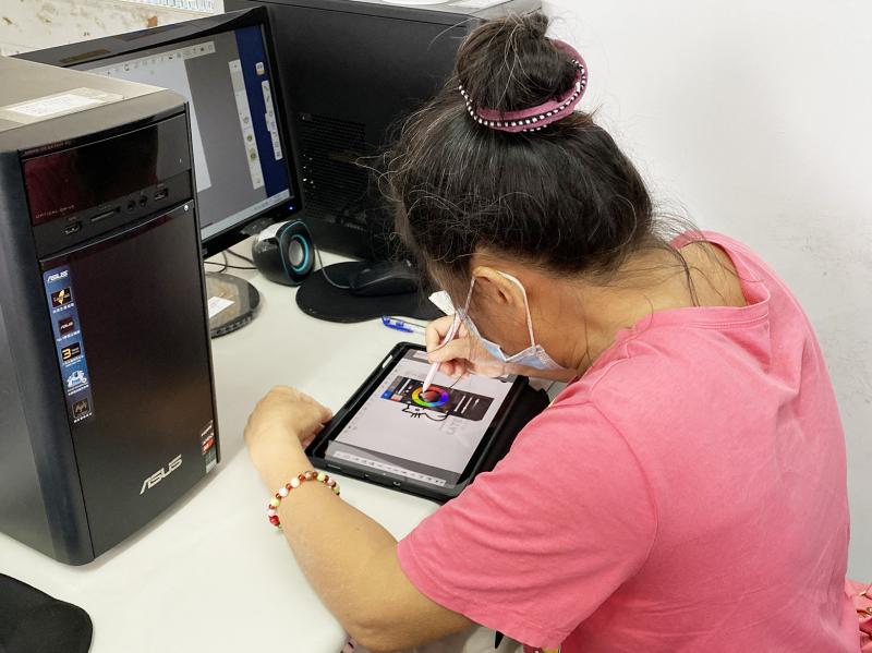 學員手拿繪圖筆,在平板上繪製插圖