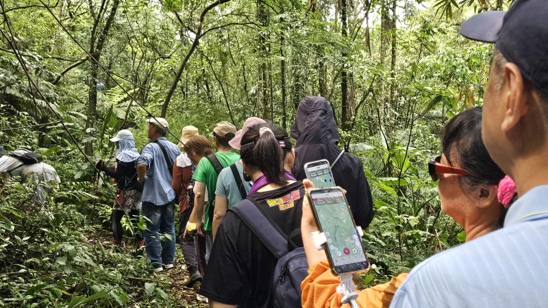 沿著山徑，學員拿起手機確認路徑軌跡是否重合。