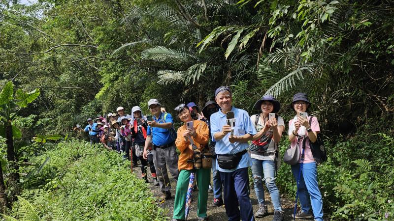學員利用手機查詢軌跡，在山徑上與手機相伴合影。