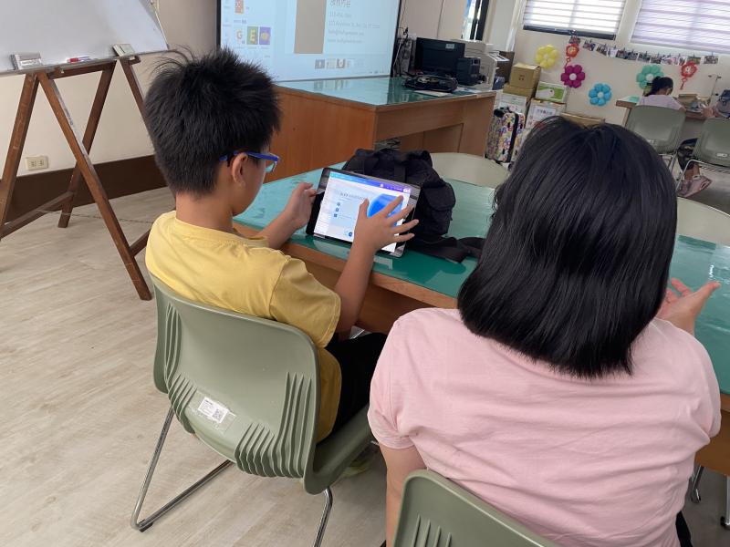 家長帶著孩子一起操作平板。