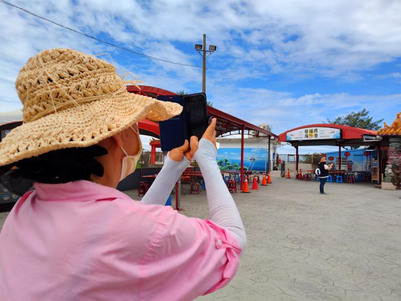 實際走出教室拍攝,照片中同學舉起手機正在拍攝土地公廟與來往香客的畫面