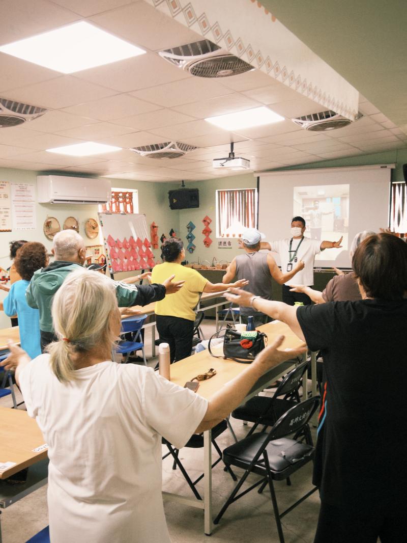 老師播放事先錄製好的音樂律動影片，並現場帶領長者們隨著影像與音樂進行三首歌曲的律動舞蹈。