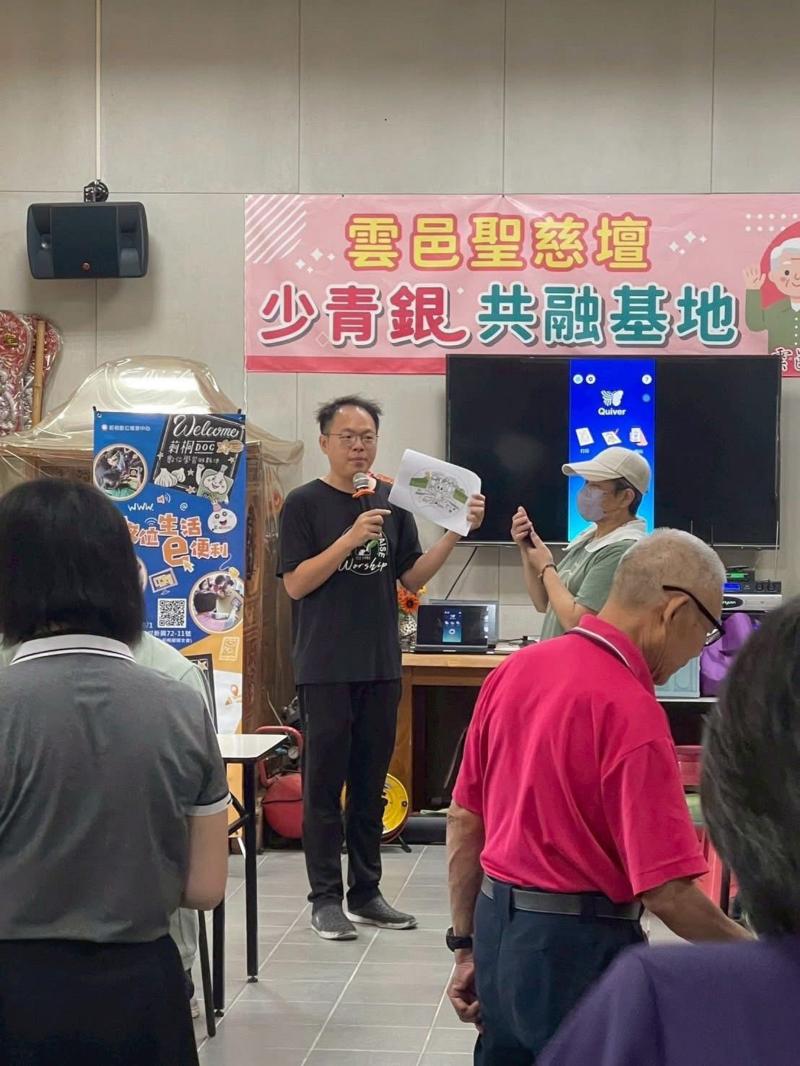 一場結合AR（擴增實境）技術的體驗活動，向現場參與者講解使用方式。螢幕顯示出AR互動畫面，可透過平板或手機掃描紙張後，畫面上浮現立體動畫或相關資訊，增加學習的趣味性與互動性。