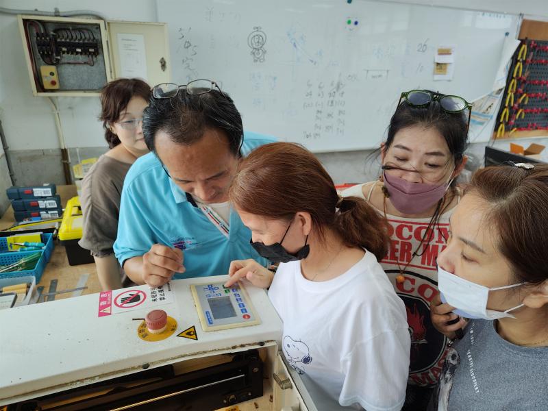 講師指導學員操作雷雕機的操作。