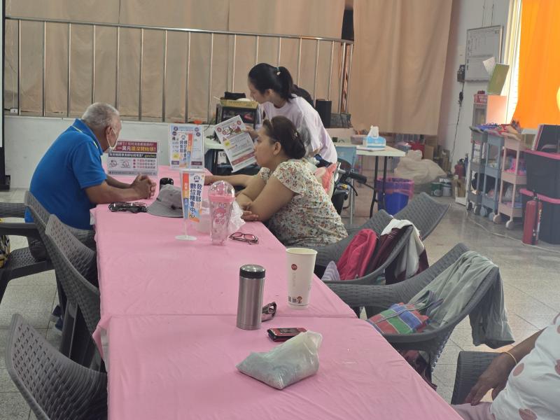 講師走下講台，正在近距離指導兩位長輩學員操作平板或回答問題。