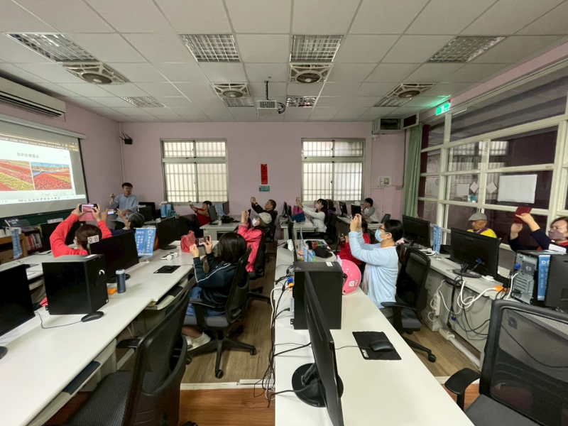 電腦教室內，陳慶元講師示範手機構圖，學員用手機拍攝投影幕。