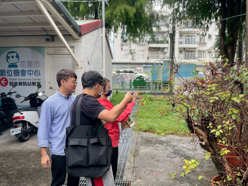 戶外植栽旁，陳慶元講師示範拍攝樹枝，學員觀察模仿。