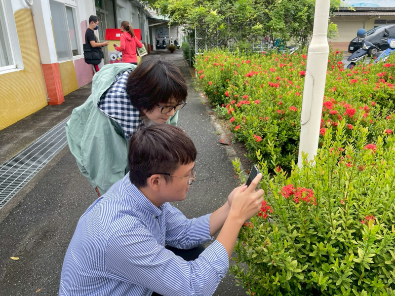 花圃旁近拍練習，陳慶元講師協助學員對準花朵。