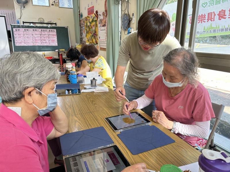 老師在旁協助學員操作平板