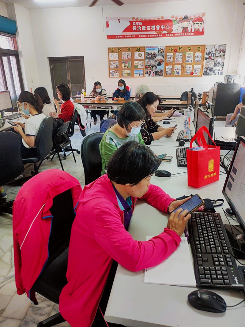 網購小編婦女專班課程，學員在電腦教室內專注操作手機，學習社群平台管理與數位行銷技巧。