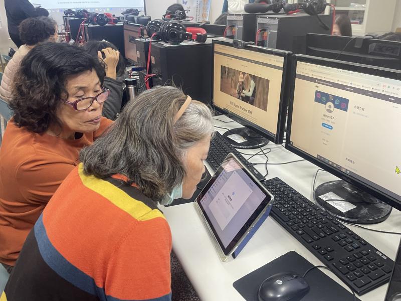 照片中兩位長輩併肩而坐,正對著 iPad 上的「語音備忘錄」功能進行深度練習,後方的電腦螢幕則顯示著 Apple Teacher 的認證歷程。