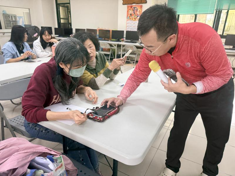 老師指導樂齡幹部怎麼操作手機的介面