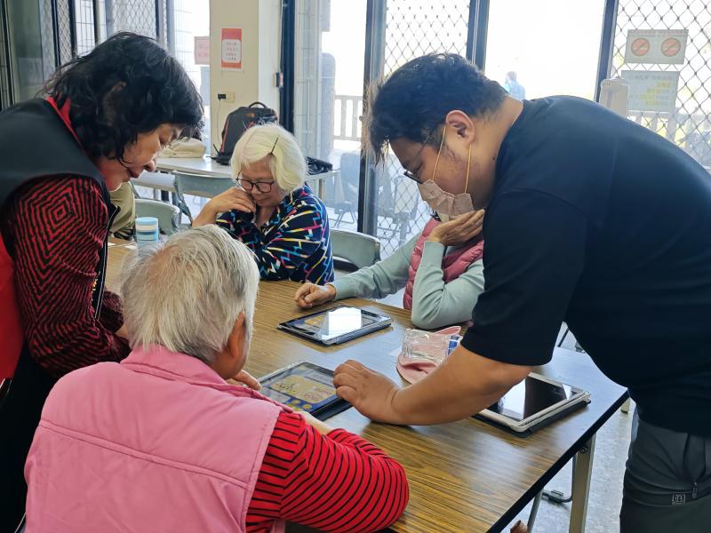 課堂中，長輩們在熟悉的鄰里空間內專注學習平板攝影與 Google 語音搜尋。特別針對識字受限的學員，推廣「用說的也會通」的智慧語音功能，但因為AI目前台語不太行，我們也得帶著長輩練習說國語，讓長輩能獨立透過聲音查詢氣象、健康資訊及防災宣導，