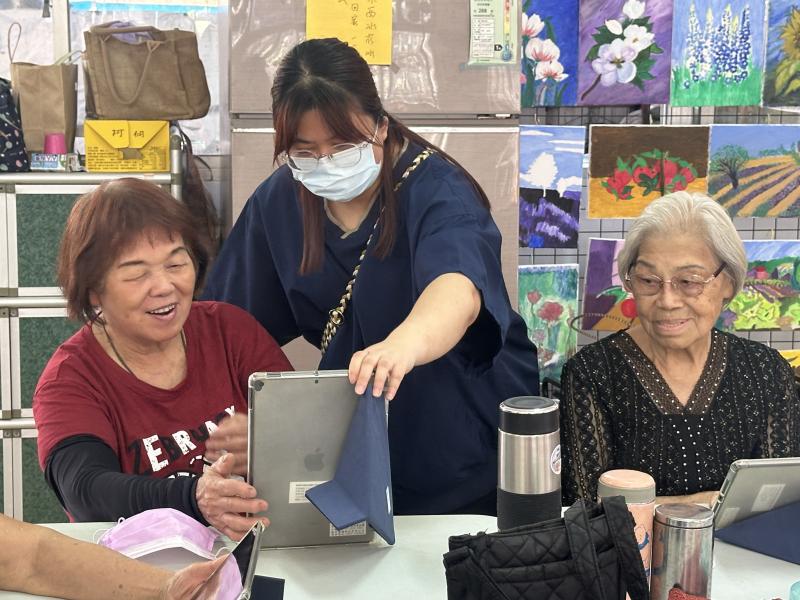 培育社區人才，站長也幫忙長輩平板在課堂上的操作方式.