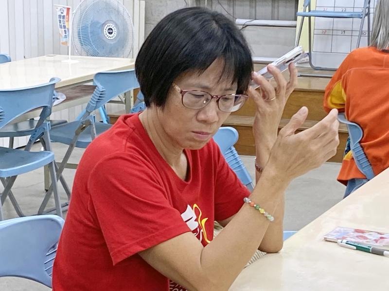 學員將手機靠近耳朵，試聽為影片挑選的音樂