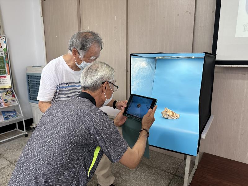 大哥拿著平板、對著燈箱裡的貝殼盯超久,這認真拍商品照的架勢完全是大師級!