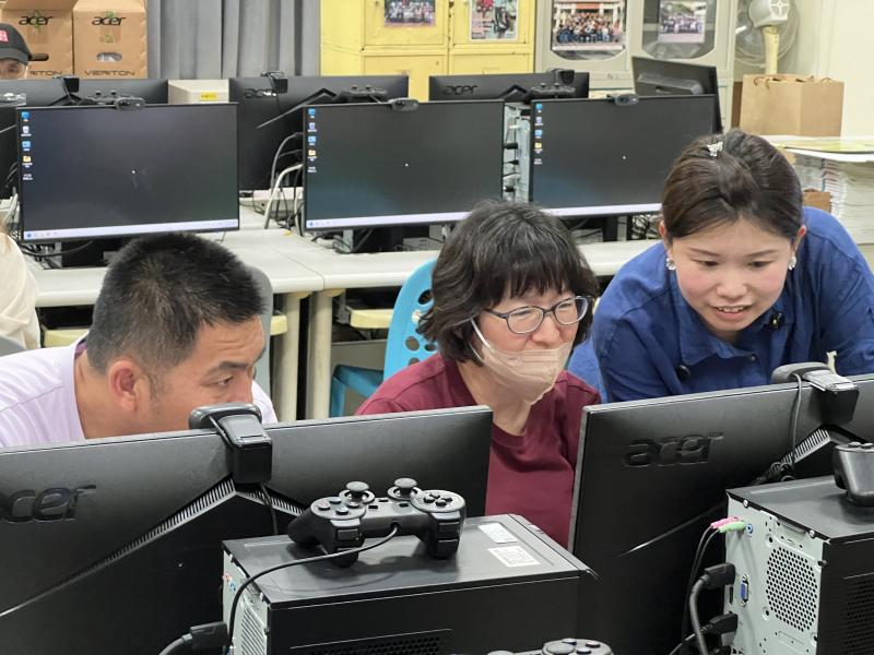 學員們圍坐電腦教室,專注討論包裝設計課程內容,老師在一旁協助說明